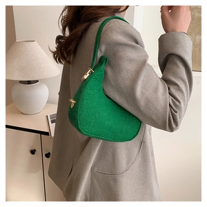Chic green felt handbag with crocodile texture and gold hardware on a grey suit model