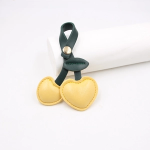 Close-up of heart-shaped cherry leather cable organizer with metal snap button