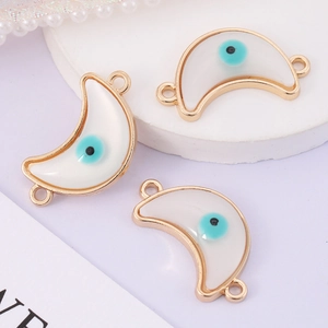 Macro shot of three white crescent evil eye connectors with gold trim for DIY jewelry