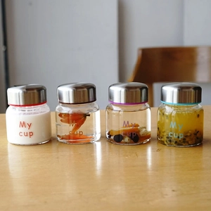 Four 150ml mini glass jars with metal lids and colorful silicone rings on wood table