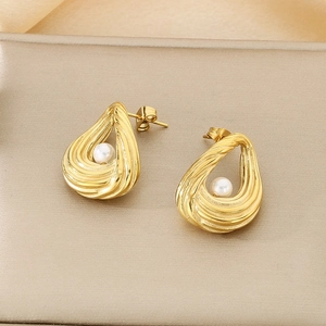Detailed macro view of gold hollow oval earrings with white pearls on silk