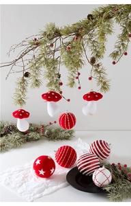 Close-up of red and white mushroom and patterned ball ornaments hanging on pine branches