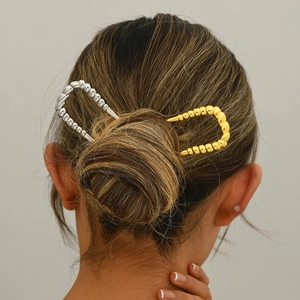 Set of gold and silver U-shaped hair pins shown on a model's elegant bun hairstyle