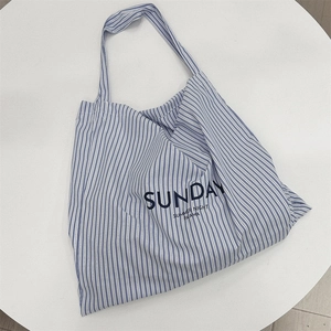 Detail of blue and white striped canvas tote bag with Sunday Summer Night text on table
