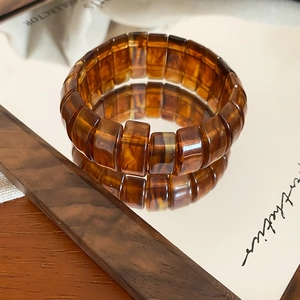 Macro shot of amber resin stretch bracelet with tortoiseshell patterns on mirror surface