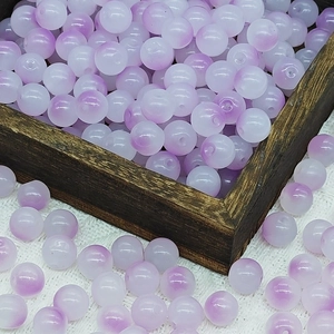 Close-up of 10mm white and purple gradient glass beads spilling from a wooden box onto fabric