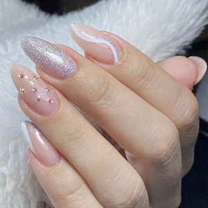 Almond teardrop press-on nails with nude pink base, silver glitter, and rhinestone accents