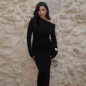 Détail d'une élégante robe longue noire asymétrique à coupe moulante et fronces