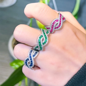 Detailed view of criss-cross ruby rings with colorful pavé stones on a model's hand