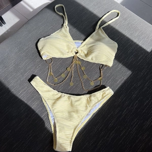 Two-piece yellow textured bikini set with gold chain detail and high-cut bottoms