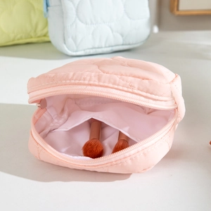 Detailed view of pink quilted cosmetic bag with soft puffy texture and zipper closure