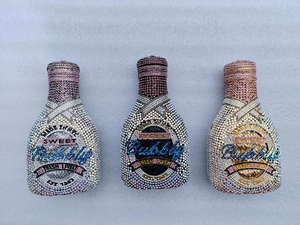 Three champagne bottle clutch bags with sparkling rhinestones and colorful text designs