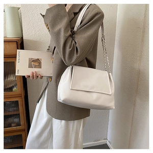 Chic white chain strap shoulder bag held by a model in a modern minimalist setting
