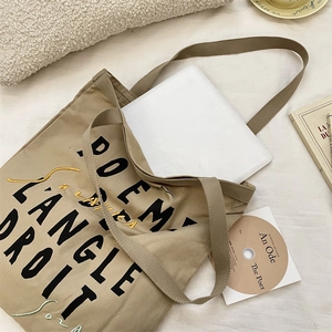 Detail of khaki canvas tote bag with French poem print and embroidery in a cozy setting