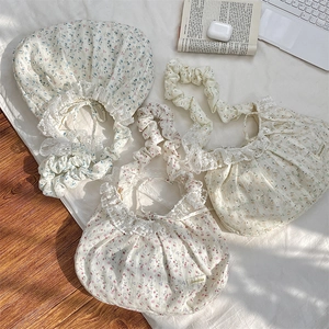 Détail de trois sacs cabas à fleurs avec dentelle et bandoulières plissées sur un lit