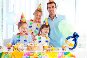 Family wearing glowing LED bulb necklaces at a happy birthday party with colorful decor
