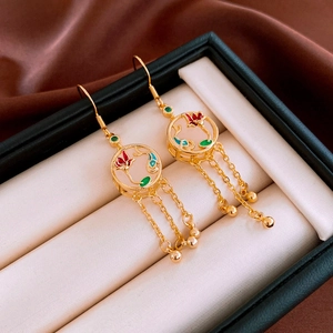 Détail de boucles d'oreilles lotus dorées avec émail coloré et pompons en métal