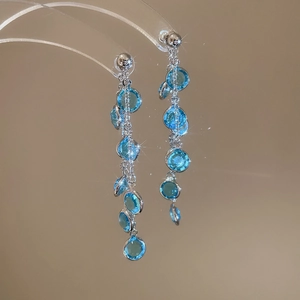 Dettaglio di orecchini placcati oro 18k con perle in vetro blu e lunghe nappe scintillanti