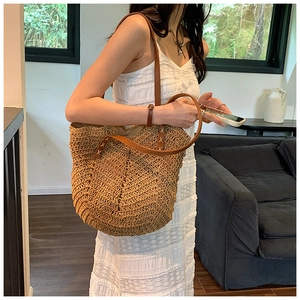 Détail du sac cabas en paille tressée avec anses en cuir marron et texture ondulée