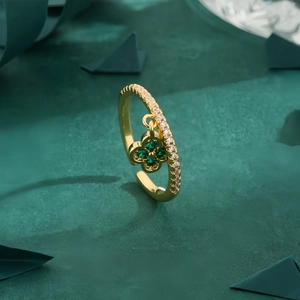 Adjustable gold clover pendant ring featuring emerald green and white zircons on dark base
