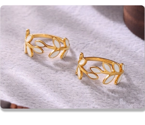 Close-up of two gold 18k plated stainless steel leaf rings with white enamel finish