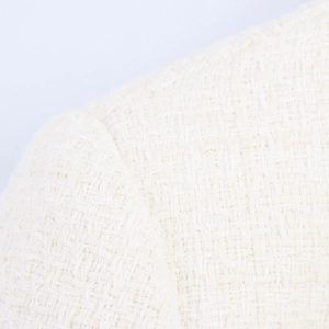 Macro shot of cream tweed fabric showing detailed woven texture of the two-piece set