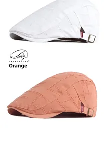 Detail von Schiebermützen in Weiß und Orange mit Schnallen und modischen Etiketten