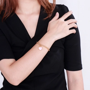 Detail of beaded 18k gold plated bracelet with a pink heart pendant on a model wrist
