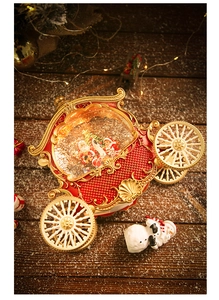 Close-up of a vintage Christmas pumpkin carriage snow globe with festive light on wood