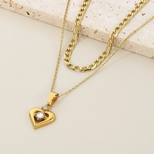 Detail of gold double-layered heart necklace with zircon stone on stone prop