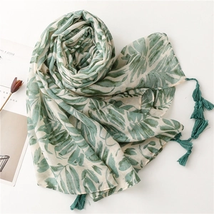 Detail of green leaf print scarf with handcrafted tassel fringe and linen texture