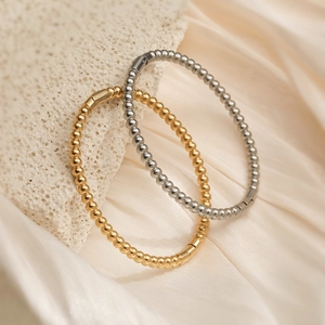 Minimalist 18K gold and silver beaded titanium steel bracelets on white stone
