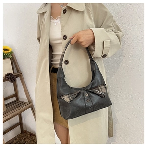 Detail of grey vintage shoulder bag featuring a plaid bow and retro button accents