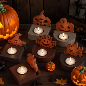 Halloween candle holders with pumpkin and scarecrow silhouettes on a rustic wood surface