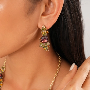 Macro view of gold-plated geometric earring with red square stone and floral crystals