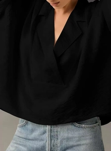 Detail of the elegant deep V-neckline and smooth silk-like texture of this black shirt