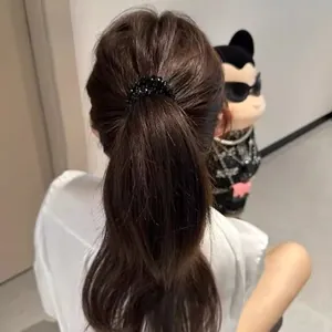 Detail shot of a black beaded elastic hair tie worn on a ponytail for a sleek look