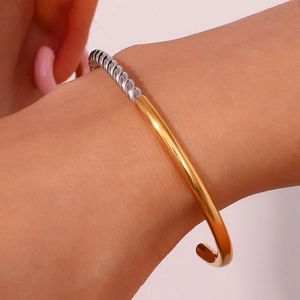 Polished gold and silver twisted open bangle bracelet with a minimalist mixed metal design