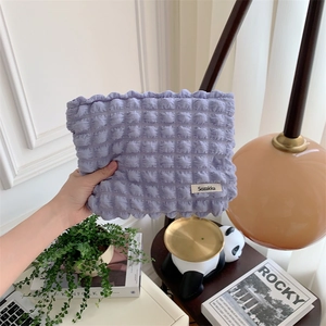 Close-up of purple bubble textured canvas makeup bag with a minimalist brand label