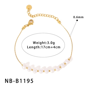 Détail d'un bracelet en perles dorées avec fermoir mousqueton et chaîne d'extension