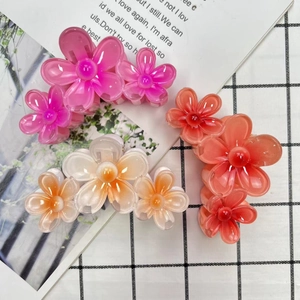 Detailed close-up of colorful frangipani hair claws in pink, orange and white resin
