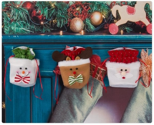 Close-up of Santa, Reindeer, and Snowman drawstring gift bags hanging by the fireplace