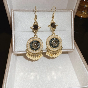 Detail of bohemian drop earrings with gold sequins, pearls and dark gemstones