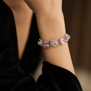 Detail of pink square gemstone and floral charm silver bracelet worn on wrist