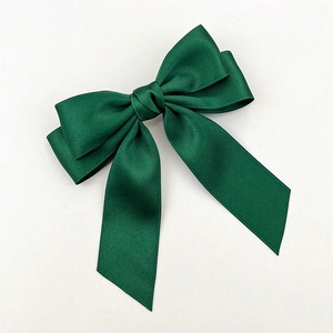 Macro view of dark green silk ribbon bow hair clip with elegant satin texture finish