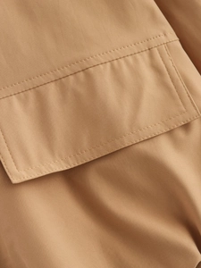 Macro shot of khaki windbreaker pocket flap showing premium twill fabric and stitching