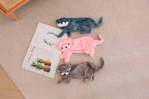 Detailed view of plush otter pouches in blue, pink, and grey on a cozy woven rug
