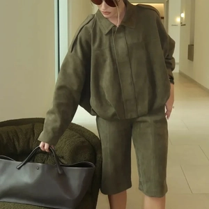 Detail view of olive green suede pilot jacket with shoulder buttons and high-waist shorts