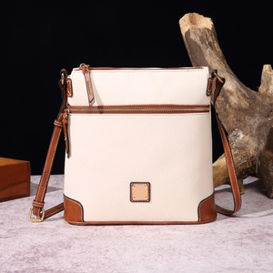 Detail of pebbled leather crossbody bag with brown trim and gold-tone zipper hardware