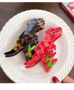 Detail of red and tortoiseshell dinosaur hair claws on a white vintage ceramic plate